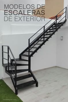 a black stair case next to a white wall and green grass in front of it