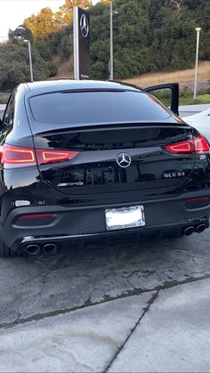 the rear end of a black car parked in a parking lot