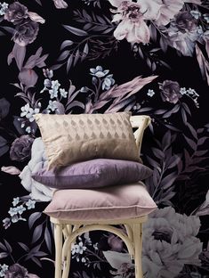 three pillows stacked on top of each other in front of a floral wallpaper