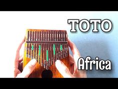 a person holding an african musical instrument with the words toto in front of it