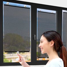 a woman pointing at the screen on a window that has roller shades in front of it