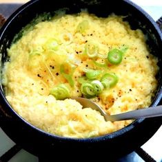 a bowl filled with mashed potatoes and green onions on top of a stovetop