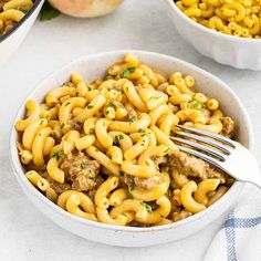 two bowls filled with macaroni and cheese on top of a white tablecloth