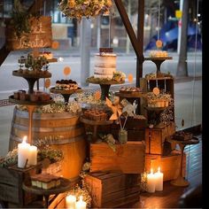 a table topped with lots of wooden barrels filled with cakes and candles next to each other