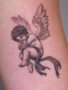 an angel tattoo on the leg of a woman's thigh, holding a baby