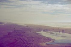 an aerial view of a beach with water and people walking on the sand near it