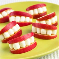 apples and marshmallows arranged in the shape of teeth on a green plate