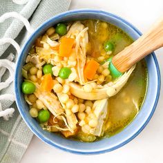 a bowl of soup with peas, carrots and corn in it next to a towel