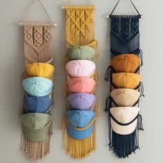 three wall hangings with hats and tassels attached to each one on the wall