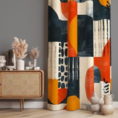 an abstract shower curtain with orange and blue shapes on it, next to a sideboard