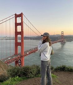 a woman standing on top of a hill next to the golden gate bridge in san francisco