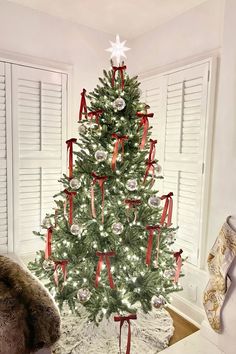 a white christmas tree with red bows and ornaments