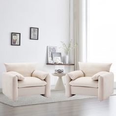 two white chairs sitting next to each other in a living room