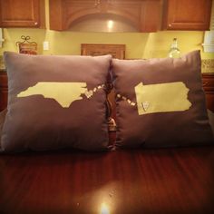 two pillows that are on top of a wooden table in front of a kitchen counter