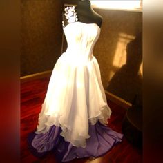 a white dress is on display in a room with wood flooring and dark walls