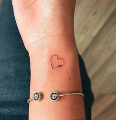 a woman's wrist with a small heart tattoo on the left side of her arm