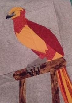 a red and yellow bird sitting on top of a piece of paper