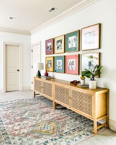 a living room with pictures on the wall and a rug in front of an entryway