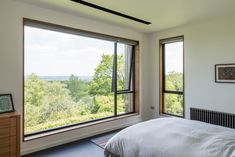 a bedroom with two large windows and a bed