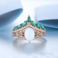 an opal and emerald ring on a white background