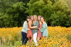 a group of women standing next to each other in a field full of yellow flowers