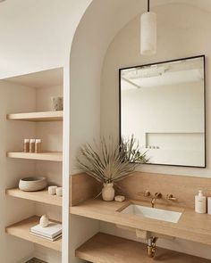 there is a mirror and sink in the bathroom with shelving on the wall next to it