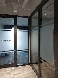 an empty room with glass doors leading to another area that has a logo on the wall