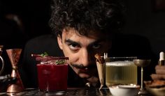 a man is looking at some drinks on the table with his face close to the camera