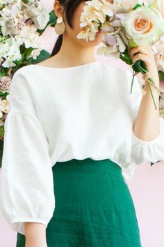 a woman holding flowers in front of a floral wall