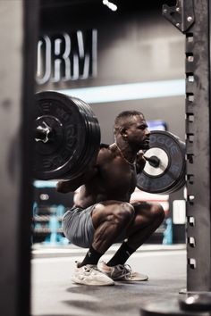 a man squatting down with a barbell in his hand