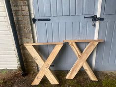 two wooden benches sitting next to each other in front of a garage door on the grass