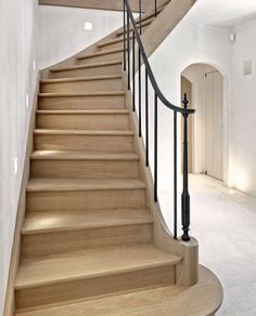 a wooden staircase with metal handrails in an empty room next to a white wall