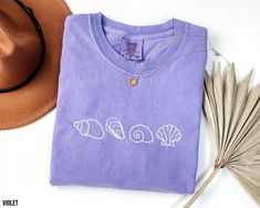 This Embroidered Comfort Colors Sea Shell shirt is a thick, structured tee that's also super soft and breathable. This cute beachy t-shirt with shell embroidery is perfect as an everyday t-shirt or great as a summer vacation gift. Design is EMBROIDERED. Please note that due to variations in monitors & lighting the colors may look slightly different in real life. DETAILS * 100% ring-spun cotton * Embroidered and shipped from the USA * Fabric weight: 6.1 oz/yd² (206.8 g/m²) * Relaxed fit SIZING * Beach Embroidered Short Sleeve T-shirt, Embroidered Short Sleeve Beach T-shirt, Embroidered Short Sleeve T-shirt For Beach, Embroidered Cotton T-shirt For Beach, Shell Embroidery, Ocean Shirt, Beach T Shirt, Beachy Vibes, Gift Design