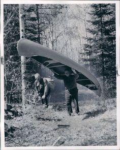 two men carrying a canoe in the woods