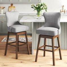 two gray upholstered bar stools in front of a white kitchen countertop