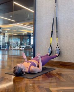 a woman is doing an exercise on a mat in the middle of a gym floor