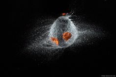 an orange and white object is splashing out of the water on a black background