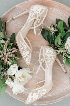 wedding shoes and flowers on a wooden platter with greenery in the middle for decoration