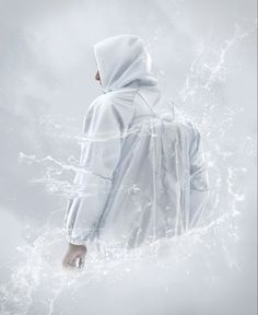 a person wearing a white raincoat standing in the water with their back to the camera