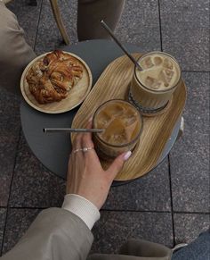 two people sitting at a table with drinks and pastries on the trays in front of them