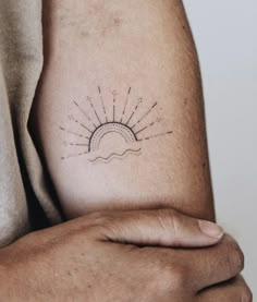 a man's arm with a sun tattoo on the left side of his arm