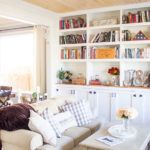 a living room filled with lots of furniture and bookshelves full of books on top of them