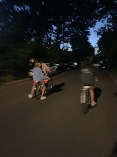 two bicyclists are riding down the street at night