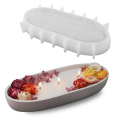 a tray with flowers and candles floating in it on a white surface, next to an object that appears to be shaped like a flower