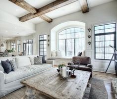 a living room filled with white furniture and lots of wood beams on the ceiling