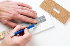 a man is measuring the height of a piece of cork with a ruler and blue pen