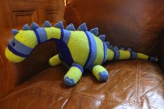 a stuffed toy sitting on top of a brown leather couch next to a pillow with blue and yellow stripes