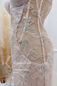 the back of a dress with beading and sequins on it, in front of a vase