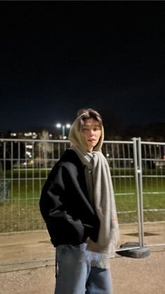 a man standing in front of a fence at night with his skateboard on the ground