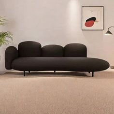 a black couch sitting on top of a carpeted floor next to a potted plant